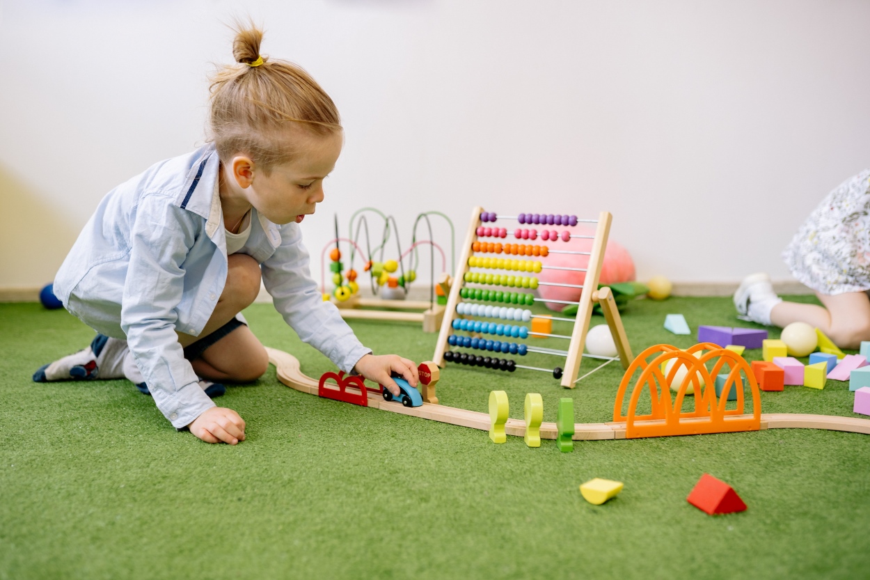 A child is playing with a toy train track