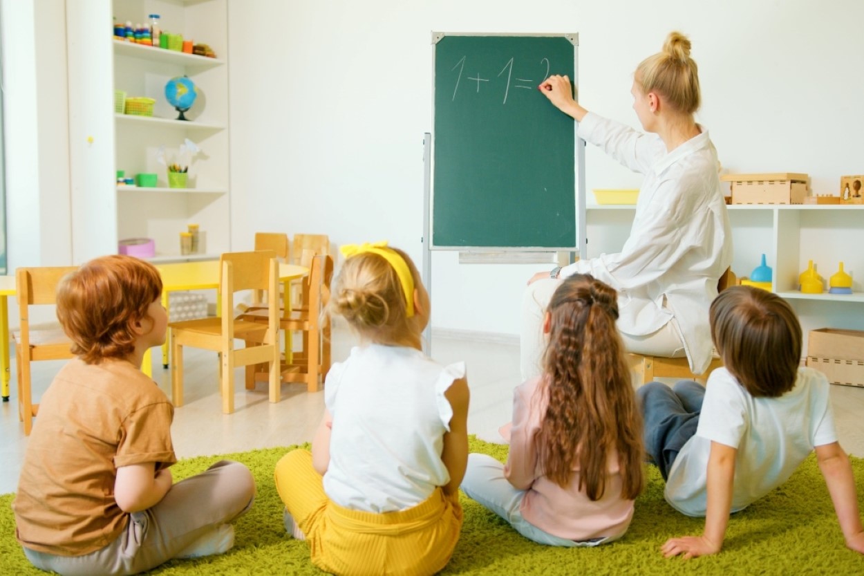 A group of children are learning maths from a chalkboard
