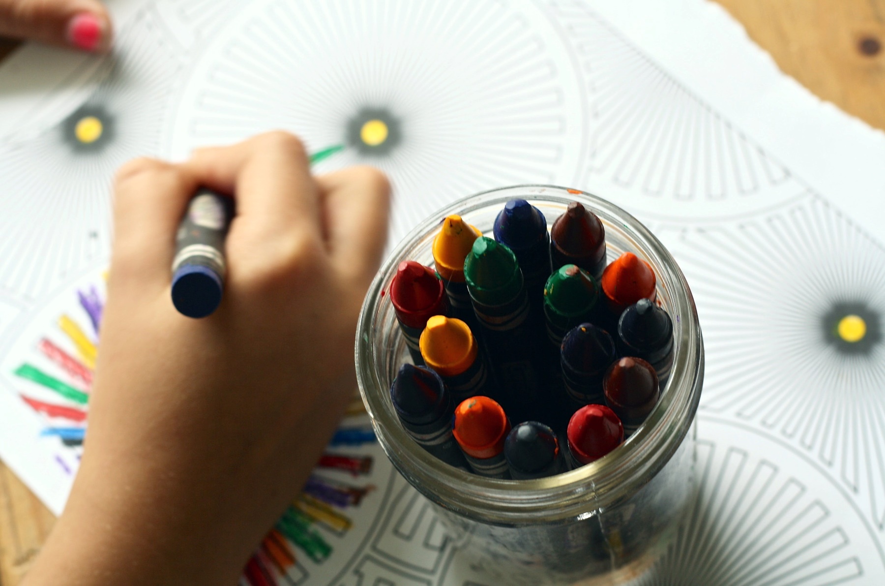 A child's hand is drawing with crayons