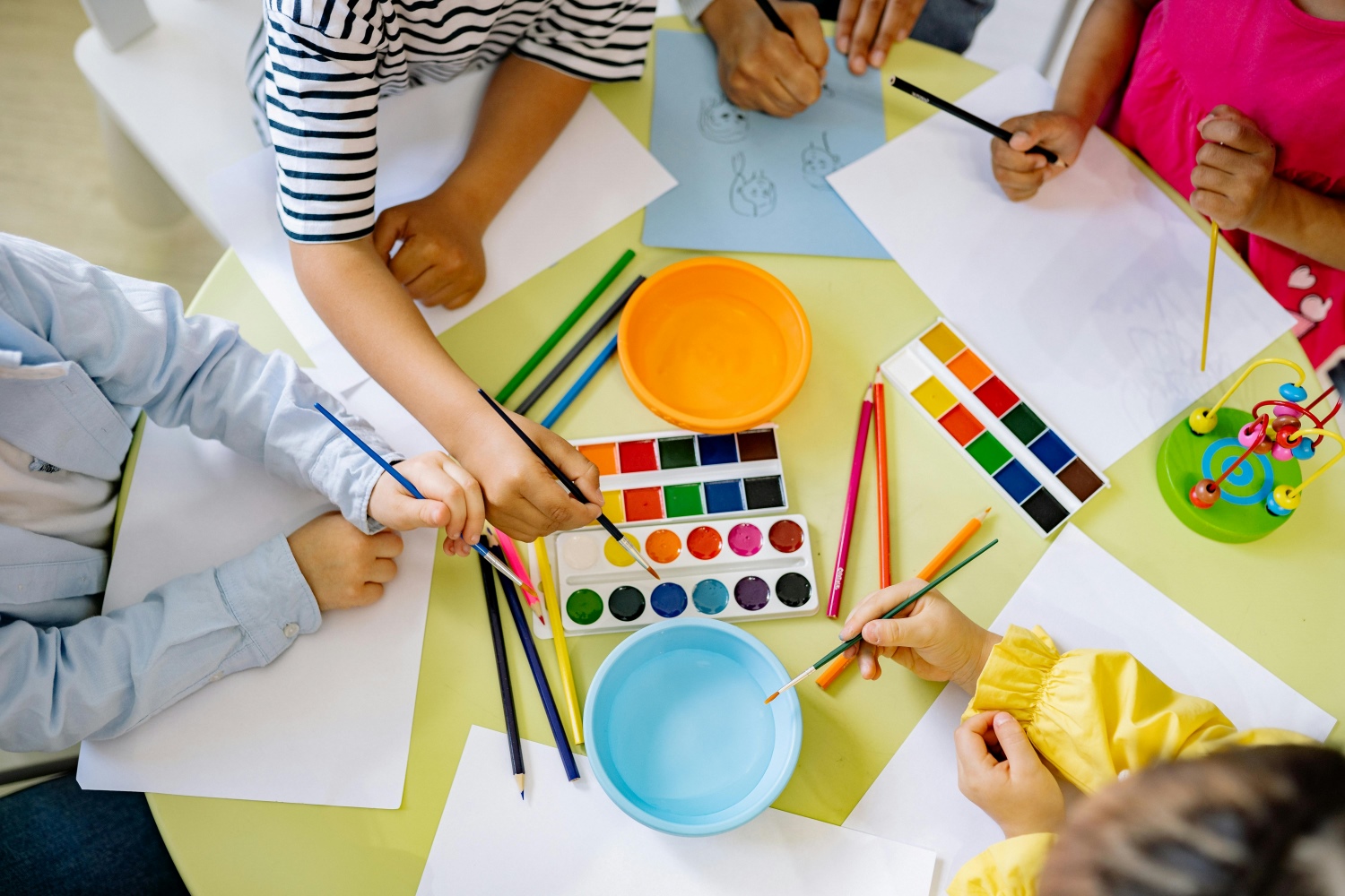 Children are painting on paper with water colours